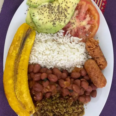 Bandeja paisa vegana con fríjoles, arroz, maduro, chorizo vegano y aguacate